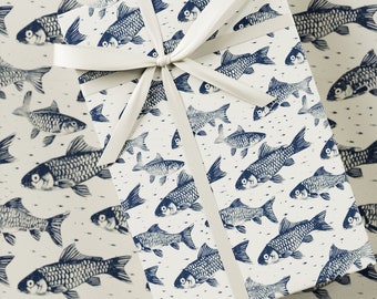 Könnte beinhalten: Eine weiße Geschenkbox mit einem blauen und weißen Fischmuster. Die Box ist mit einem weißen Band und einer Schleife verziert.