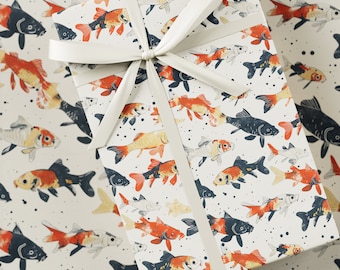 Könnte beinhalten: Geschenkbox, verpackt in weißem Papier mit einem sich wiederholenden Muster aus Koi-Fischen in Orange, Schwarz und Weiß. Oben auf der Box ist eine cremefarbene Schleife gebunden. Der Hintergrund ist das gleiche Fischmuster.