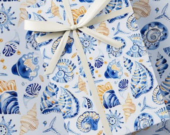 May include: A gift box wrapped in blue and gold seashell patterned wrapping paper with a white satin ribbon.