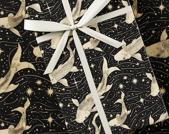 May include: Gift wrap featuring a black background with a pattern of koi fish and stars in gold. A white ribbon is tied in a bow on top of the wrapped gift. The overall theme is celestial and aquatic.
