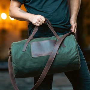 Man holding a sports bag with leather handles and waxed canvas