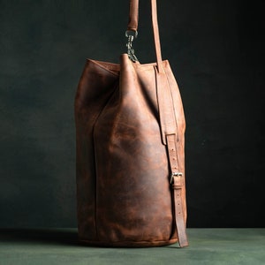 Duffel Bag made of brown crazy horse leather with a shoulder strap, adjustable and padded.