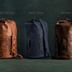 Puede incluir: Tres bolsas de viaje cil&iacute;ndricas en marr&oacute;n claro, azul marino y marr&oacute;n. Cada bolsa cuenta con un cierre enrollable, un bolsillo lateral vertical con cremallera, un asa reforzada con remaches met&aacute;licos y una correa ajustable. Las etiquetas dicen Light Brown, Navy Blue y Brown.