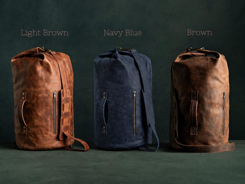Puede incluir: Tres bolsas de viaje cil&iacute;ndricas en marr&oacute;n claro, azul marino y marr&oacute;n. Cada bolsa cuenta con un cierre enrollable, un bolsillo lateral vertical con cremallera, un asa reforzada con remaches met&aacute;licos y una correa ajustable. Las etiquetas dicen Light Brown, Navy Blue y Brown.