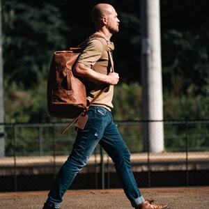 Man Walking with a Duffel Bag made of Light Brown Leather