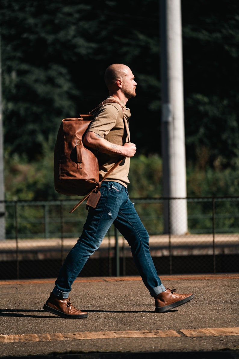 Man Walking with a Duffel Bag made of Light Brown Leather