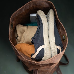 A duffel bag seen from above, with clothes and a pair of shoes inside.