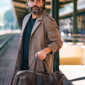 Man holding a waxed canvas travel bag