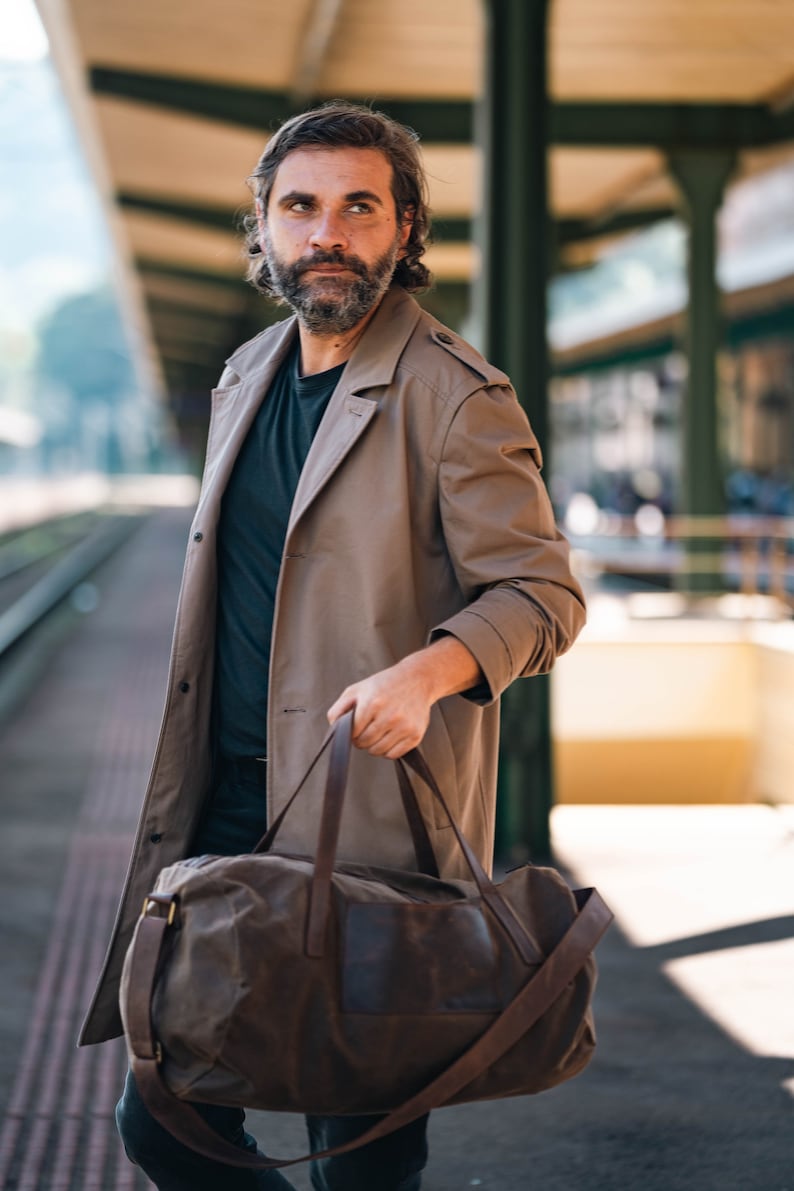 Man holding a waxed canvas travel bag