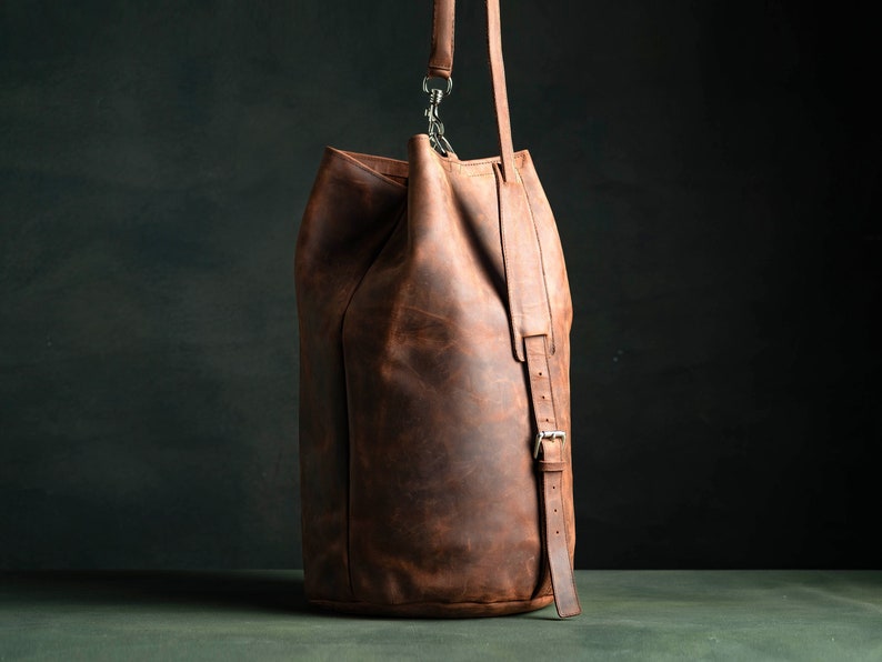 Duffel Bag made of brown crazy horse leather with a shoulder strap, adjustable and padded.