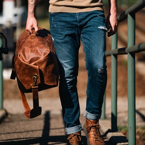 Man holding a military duffel bag made of leather