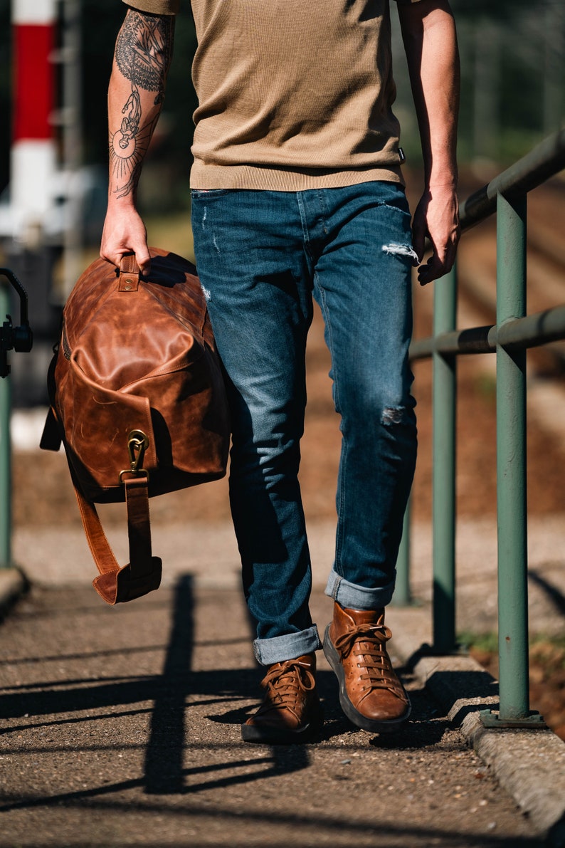 Man holding a military duffel bag made of leather