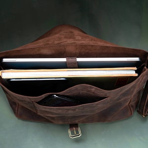 Inside of a satchel with a laptop and books and a phone