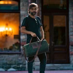 Man holding a carry-on bag by the leather handles