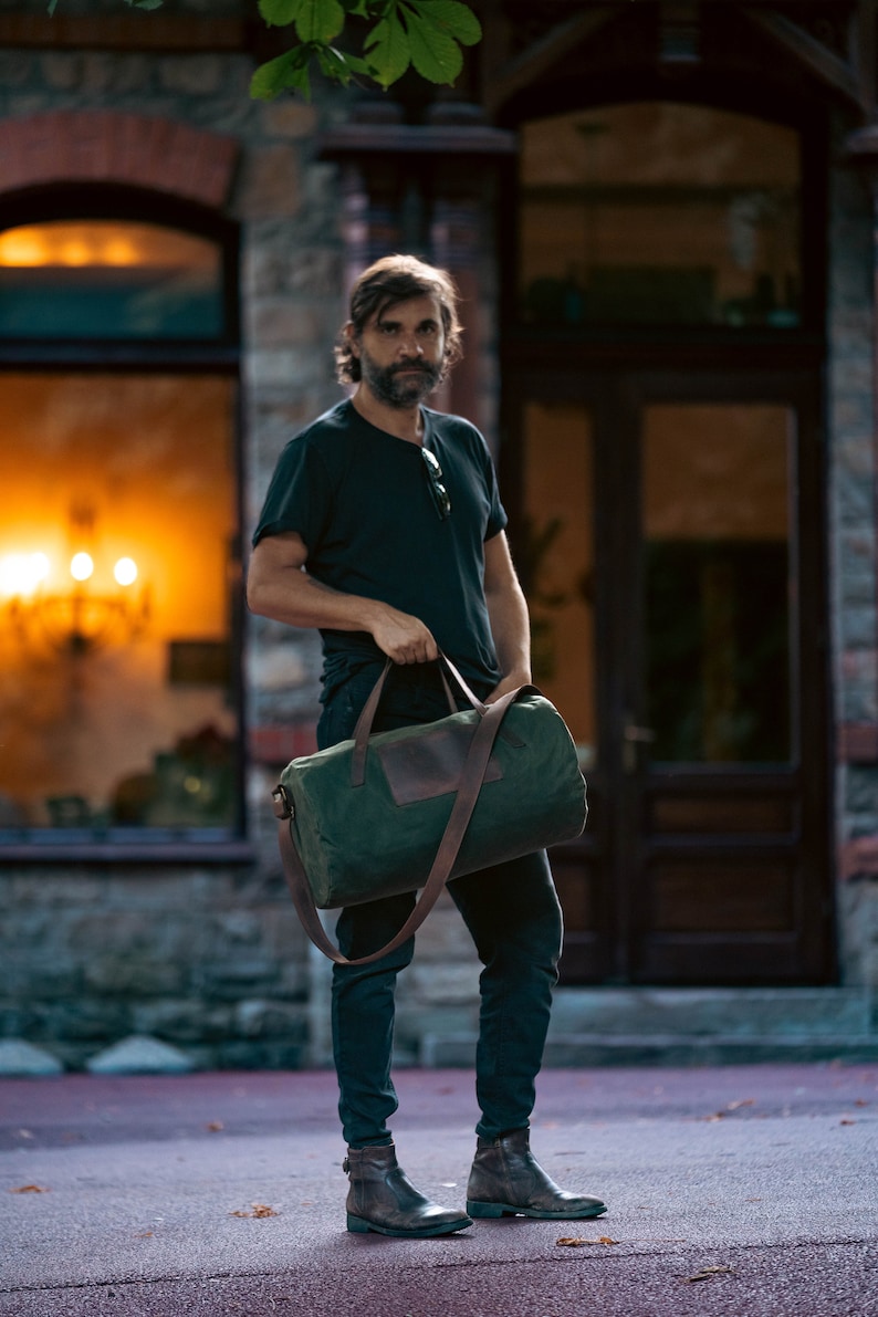 Man holding a carry-on bag by the leather handles