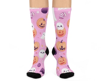 Puede incluir: Calcetines altos hasta la rodilla de color rosa con un estampado de Halloween. Los calcetines presentan calabazas de dibujos animados, fantasmas, estrellas y caramelos sobre un fondo rosa. Los talones y las puntas son negros.