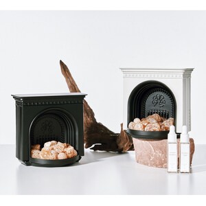 Puede incluir: Dos esculturas decorativas de chimenea, una negra y otra blanca, con un montón de piedras decorativas en cada una. Dos pequeños frascos de aceite esencial están delante de la chimenea blanca.