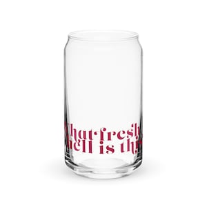 May include: A clear glass can-shaped drinking glass with the phrase "What fresh hell is this?" printed in a burgundy color. The glass is empty and sits on a white surface.