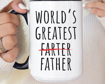 May include: White ceramic mug with a black rim and handle. The mug has black text that reads "World's Greatest" with the word "Farter" crossed out and replaced with "Father".