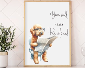 Puede incluir: Una impresión enmarcada con un perro de dibujos animados con gafas, sentado en un inodoro y leyendo un periódico. La impresión incluye el texto "You will never Pee alone!" en una fuente de escritura. El marco es de color marrón claro.