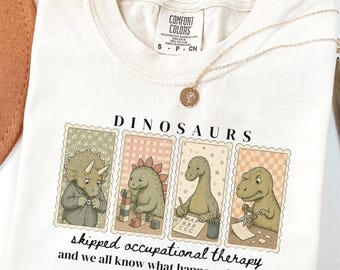 Może przedstawiać: Kremowy t-shirt z grafiką przedstawiającą cztery dinozaury w pojedynczych prostokątnych ramkach. Nad ramkami znajduje się napis DINOSAURS, a pod nimi napis skipped occupational therapy and we all know what happened to them.