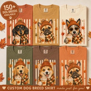 May include: Six crewneck t-shirts in various earth tones, each featuring a dog wearing a knit beanie and plaid scarf while holding a pumpkin spice latte. The shirts display a vertical striped background with autumn leaves and text 150+ DOG BREEDS AVAILABLE!