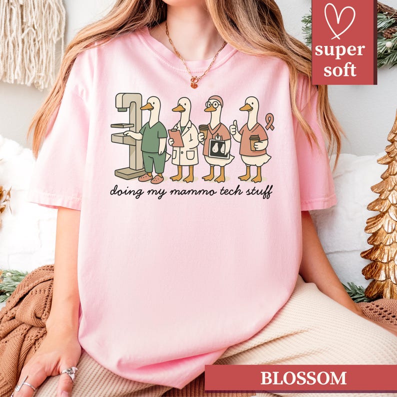 May include: Pink t-shirt with a graphic of four cartoon ducks in medical attire, including a mammogram machine. The text "doing my mammo tech stuff" is below the ducks. The shirt also has the text "super soft" and "BLOSSOM".