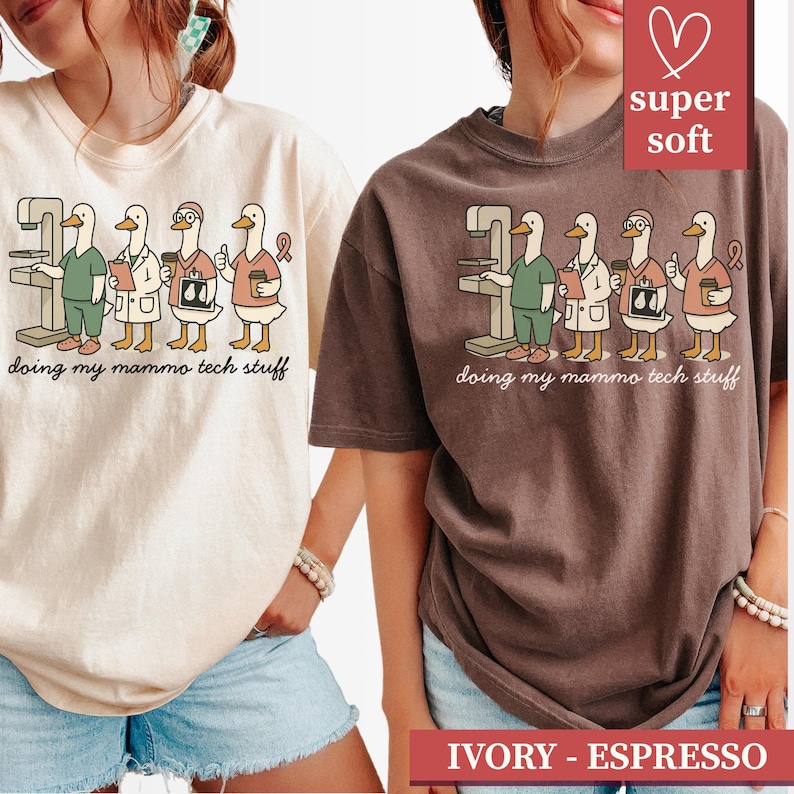 May include: Two t-shirts, ivory and espresso, feature a cartoon illustration of ducks in medical attire operating a mammogram machine. The text "doing my mammo tech stuff" is printed below the ducks. The shirts are labeled "super soft."