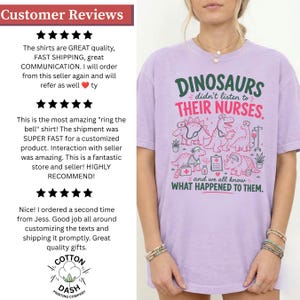 May include: A light purple short-sleeve t-shirt featuring a graphic print of cartoon dinosaurs dressed as medical professionals. The text reads: DINOSAURS didn't listen to THEIR NURSES. and we all know WHAT HAPPENED TO THEM. The design includes medical icons.