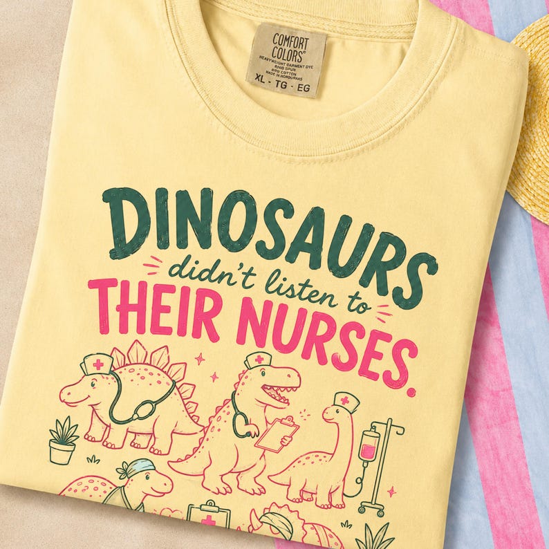 May include: A pale yellow t-shirt featuring the dark green and pink text "DINOSAURS didn't listen to THEIR NURSES." The graphic includes illustrations of four dinosaurs wearing nurse caps, with one holding a clipboard and another near an IV pole.