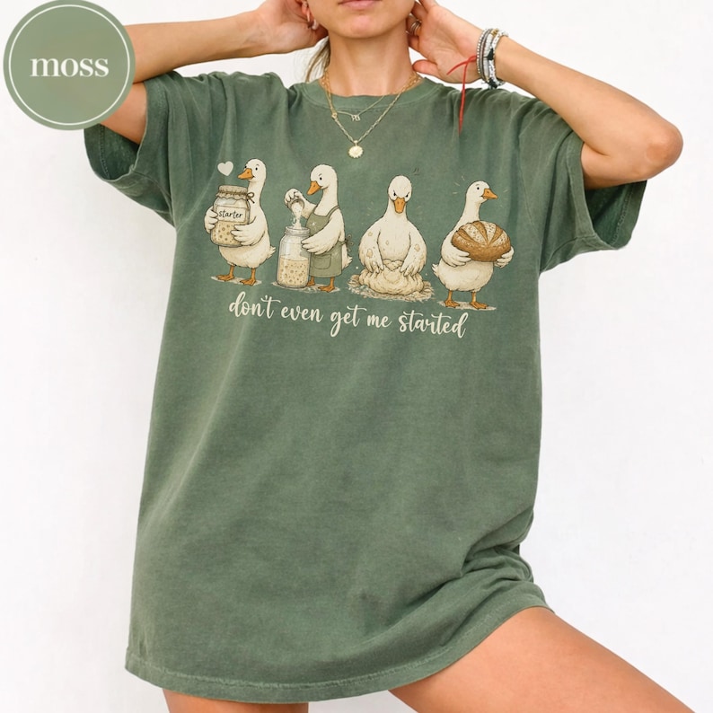 May include: Green t-shirt featuring a cartoon design of four ducks with various items: a jar, a bottle, a pile of flour, and a loaf of bread. The text "don't even get me started" is printed below the ducks.