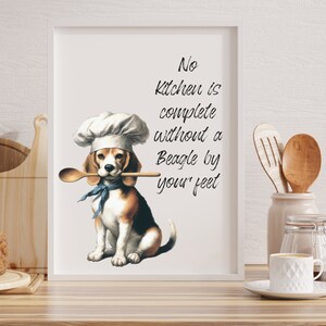 K&ouml;nnte beinhalten: Ein wei&szlig;er gerahmter Druck mit einem Beagle, der einen Kochhut tr&auml;gt und einen Holzl&ouml;ffel im Maul h&auml;lt. Der Text auf dem Druck lautet "No kitchen is complete without a Beagle by your feet."