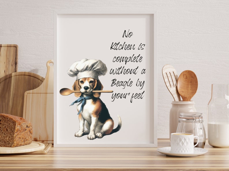 K&ouml;nnte beinhalten: Ein wei&szlig;er gerahmter Druck mit einem Beagle, der einen Kochhut tr&auml;gt und einen Holzl&ouml;ffel im Maul h&auml;lt. Der Text auf dem Druck lautet "No kitchen is complete without a Beagle by your feet."