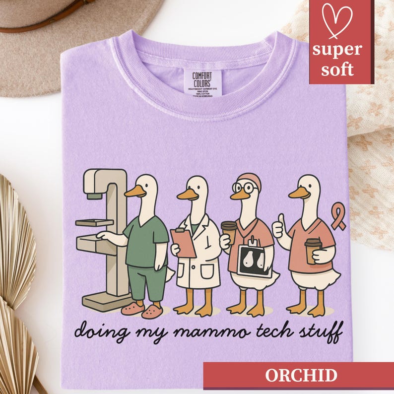 May include: A light purple t-shirt with a graphic of four cartoon ducks in medical attire. The ducks are depicted as medical professionals, with one operating a mammogram machine. The text "doing my mammo tech stuff" is below the graphic.
