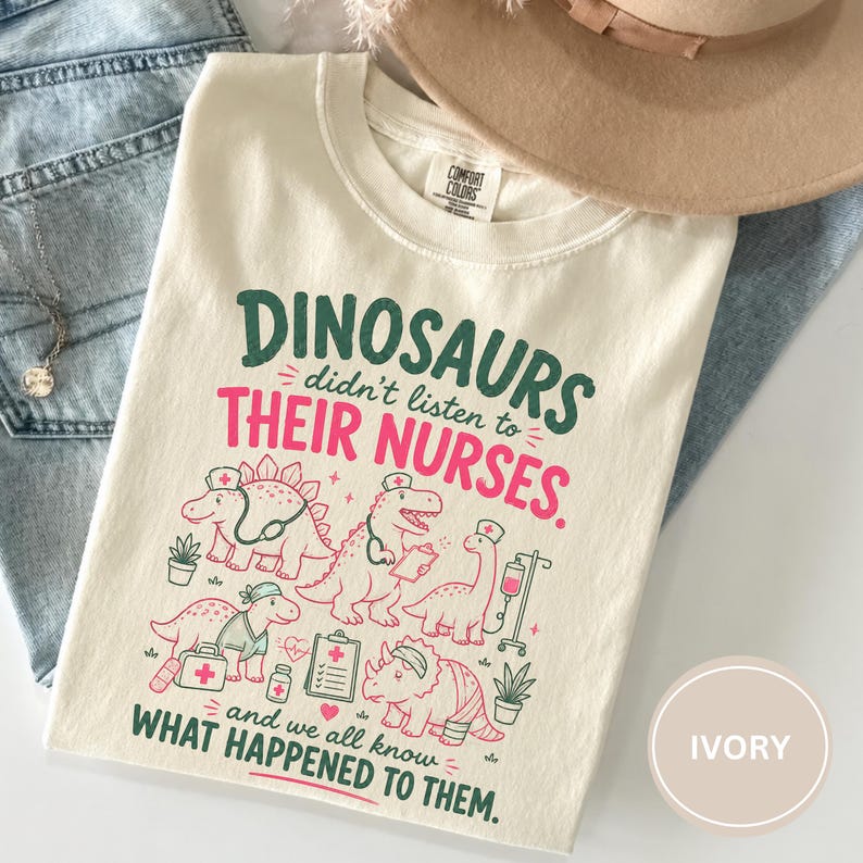May include: An ivory crew neck t-shirt featuring a graphic print with the text "DINOSAURS didn't listen to THEIR NURSES. and we all know WHAT HAPPENED TO THEM." The design includes illustrations of five dinosaurs wearing nurse caps and medical gear.