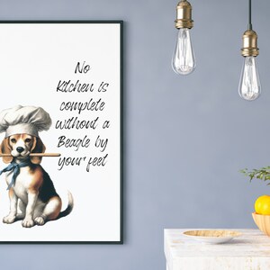 K&ouml;nnte beinhalten: Ein wei&szlig;er gerahmter Druck mit einem Beagle, der einen Kochhut tr&auml;gt und einen Holzl&ouml;ffel im Maul h&auml;lt. Der Text auf dem Druck lautet "No kitchen is complete without a Beagle by your feet."