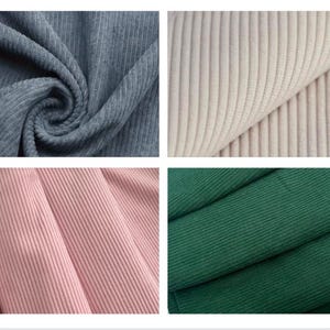 May include: Four fabric swatches in different colors: blue-grey, off-white, light pink, and dark green. Each swatch displays a ribbed corduroy texture, with vertical ridges running across the fabric. The fabric is folded and draped, showcasing the texture and color variations.