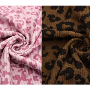 May include: Two swatches of fabric, one pink and one brown, both with a leopard print pattern. The pink fabric has a light pink background with darker pink spots. The brown fabric has a brown background with black spots. Both fabrics are ribbed.
