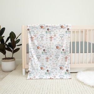 Pu&ograve; includere: Una copertina per neonati bianca con un motivo ripetitivo di immagini religiose, tra cui croci, calici e una figura di Ges&ugrave;. La copertina &egrave; drappeggiata su una culla bianca con un materasso grigio.