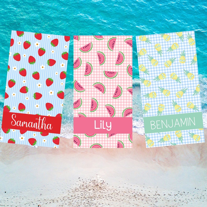 May include: Three personalized beach towels with different patterns. The first towel has a blue and white striped background with red strawberries and white flowers. The second towel has a pink and white gingham background with watermelon slices. The third towel has a blue and white gingham background with yellow pineapples wearing sunglasses. The towels are labeled "Samantha", "Lily", and "Benjamin".