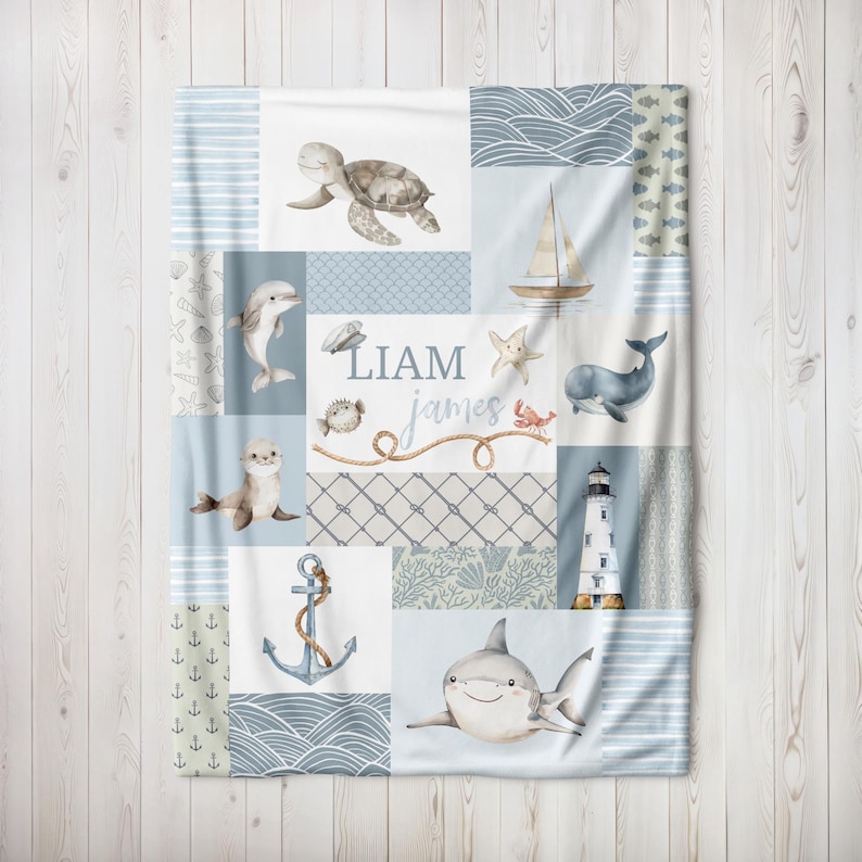 May include: A blue and white baby blanket with a patchwork design featuring sea creatures, a lighthouse, an anchor, and the names Liam James.