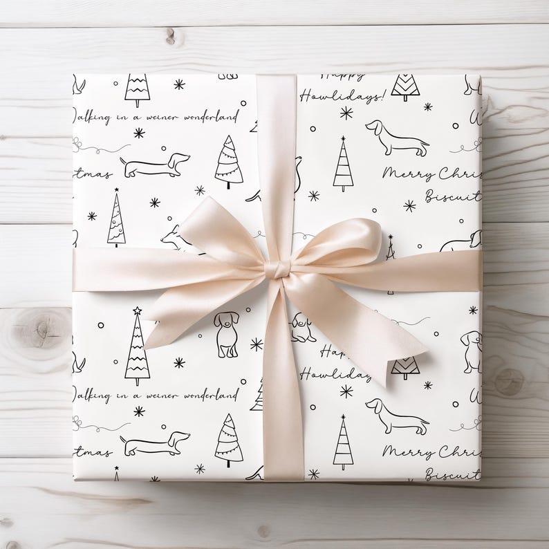 May include: White gift wrap with a black and white dachshund and Christmas tree pattern. The wrapping paper has the text "Happy Howlidays!" and "Merry Christmas Biscuit" repeated on it. The gift is tied with a beige ribbon.