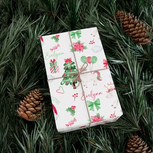 May include: White wrapping paper with a Christmas theme featuring a unicorn, a Christmas tree, candy canes, holly, and the name "Evelynn" repeated twice.