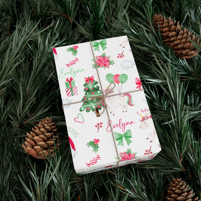 May include: White wrapping paper with a Christmas theme featuring a unicorn, a Christmas tree, candy canes, holly, and the name "Evelynn" repeated twice.