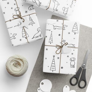 May include: White wrapping paper with a black and white illustration of a dachshund dog, a Christmas tree, and the words "Christmas" and "winter wonder".