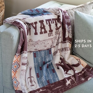 May include: A white fleece blanket with a southwestern design. The blanket features a brown and blue pattern with a guitar, arrows, and the text "WYATT EST. 2021".