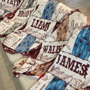 Five personalized western-themed baby blankets displayed on couch, each with custom name and rustic cowboy design in colors: blue, maroon, sage, red, and brown