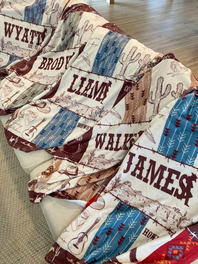 Five personalized western-themed baby blankets displayed on couch, each with custom name and rustic cowboy design in colors: blue, maroon, sage, red, and brown