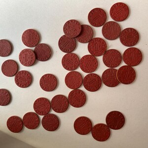 Może przedstawiać: Kolekcja małych, okrągłych, czerwonych żetonów rozrzuconych na białej powierzchni. Każdy żeton zawiera cyfrę "1" oraz słowa "RED POINT OPA" ułożone w okrąg. Żetony wydają się być wykonane z gęstego materiału.