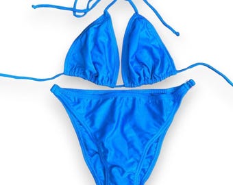 May include: A bright blue bikini set, featuring a triangle top with tie straps and a matching low-rise bottom. The swimwear is made of a smooth, shiny fabric, perfect for a day at the beach or pool.
